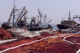 Image du Maroc Professionnelle de  Quelques ouvriers s'activent à réparer les filets de pêche sur un des quais au port d'Agadir, ville située au sud du Maroc, Vendredi 23 Août 2002. (Photo / Abdeljalil Bounhar)

 